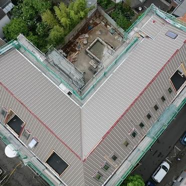 Neues Dach in Bauphase Luftaufnahme eines großen Gebäudedachs mit Gerüst und laufenden Bauarbeiten.