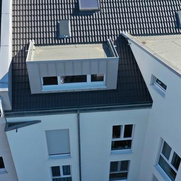 Dachsanierung mit Gaubeneinbau Luftaufnahme eines Wohnhauses mit frisch gedecktem Dach und moderner Fenstergaube.