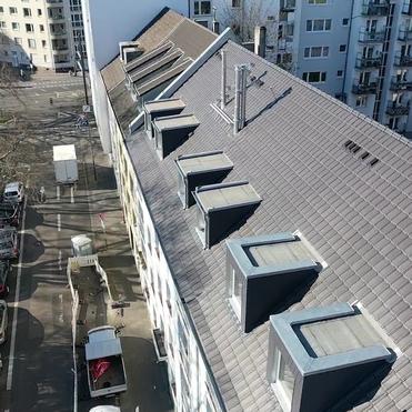 Langes Wohnhausdach mit mehreren neuen Gauben und professionell eingedeckten Dachziegeln.