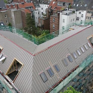 Gro&szlig;es Geb&auml;udedach mit Ger&uuml;st, Dachfenstern und laufenden Ausbauarbeiten.