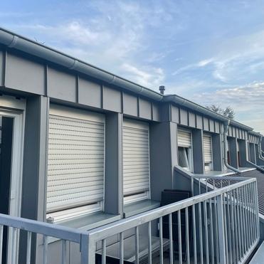 Elegante Metallverkleidung und Fensterl&auml;den an einem Stadthaus, fachm&auml;nnisch installiert von einer Bauklempnerei bei D&auml;mmerung.