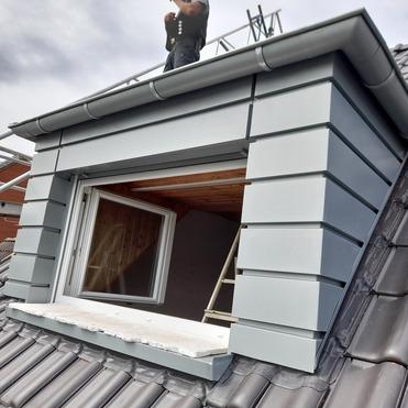 Handwerker arbeitet an moderner Gaube mit Metallverkleidung und eingebautem Dachfenster.