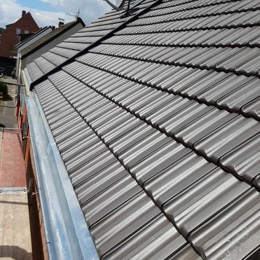 Schr&auml;gdach mit neuen dunkelgrauen Dachziegeln, Sat-Sch&uuml;ssel und sauberer Regenrinne.